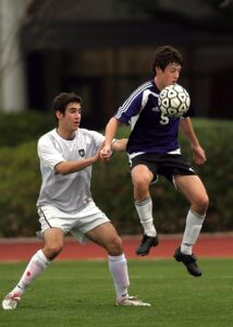 Two teens engaged in an intense outdoor soccer game, focusing on skill and strategy.