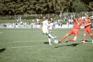 Exciting soccer match with athletes competing on a sunny field, showcasing action-packed gameplay.